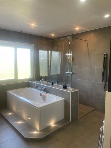 La grande salle de bains est pourvue d'une baignoire et d'un miroir. dans l'établissement Villa Le Leard, à Allonnes