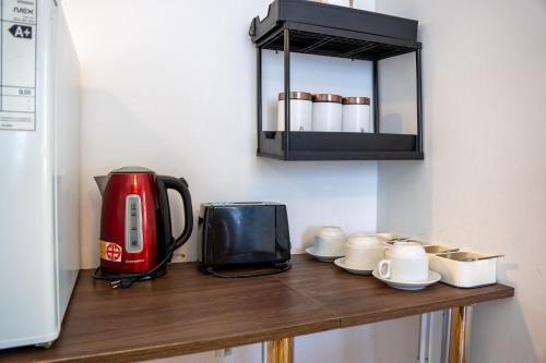 a counter with a coffee maker and a toaster and cups at Hotel Boutique El Parque in Concepción
