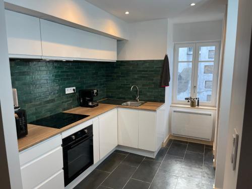 une cuisine avec des armoires blanches et un évier dans l'établissement Ti Korn, à Billiers