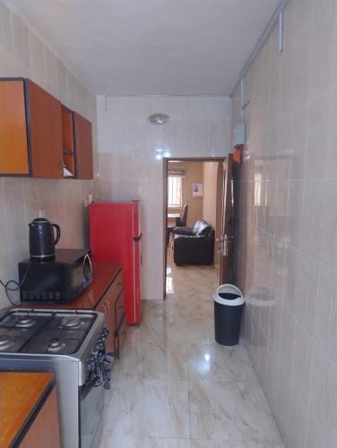 a kitchen with a stove and a red refrigerator at The Homely Hideout in Ajegunle