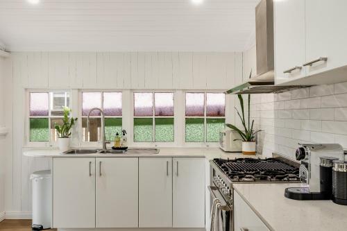 a white kitchen with a sink and a stove at Bondi Cottage on Queens Park! in Toowoomba