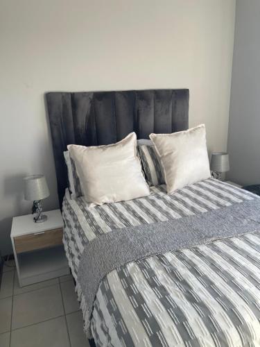 a bedroom with a bed with a striped blanket and pillows at Beautiful 2 bedroom apartment in strand in Somerset West