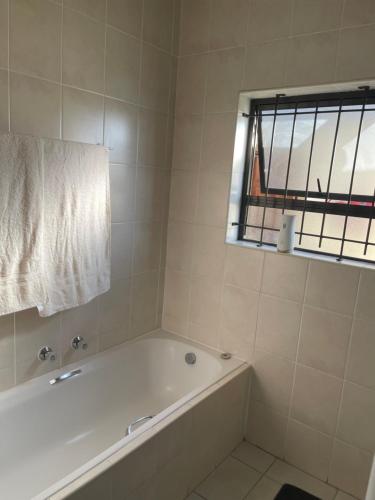 a white bathroom with a tub and a window at Beautiful 2 bedroom apartment in strand in Somerset West
