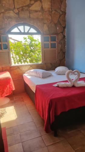 two beds in a room with two swans on them at Pousada Iansã in Vera Cruz de Itaparica