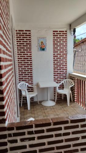 a patio with two chairs and a white table and chairs at Pousada Iansã in Vera Cruz de Itaparica