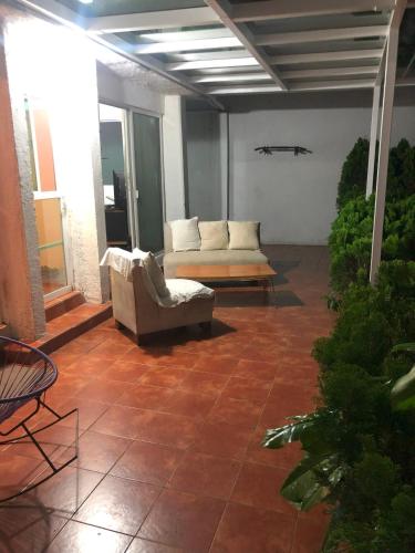 a living room with a couch and a chair on a patio at Casa de descanso con alberca y billar en Cuernavaca in Cuernavaca