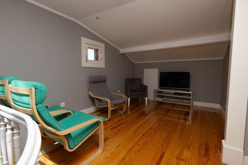 a living room with two chairs and a television at ALM SANTA LUZIA in Guimarães
