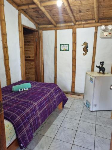 a bedroom with a purple bed and a refrigerator at Bora Bora Bungalows in Los Órganos