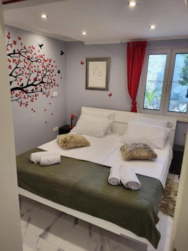 a bedroom with a large bed with a tree on the wall at Villa Amarila in Podaca