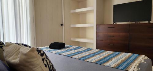 a bedroom with a bed with a dresser and a flat screen tv at Kin Tulum House downtown in Tulum