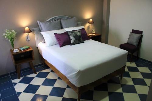 a bedroom with a large white bed and a chair at Entre Patios Hotel Boutique in León