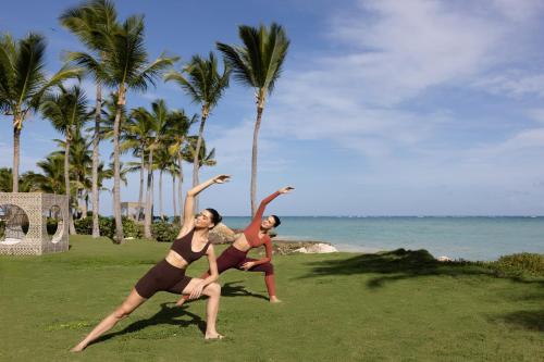 two women are dancing on the beach with palm trees at Sanctuary Cap Cana, a Luxury Collection Resort, Dominican Republic, Adult All-Inclusive in Punta Cana