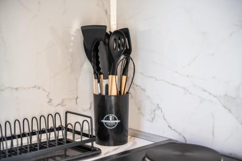 a black cup filled with utensils next to a wall at RAOS Cottage in Ulcinj