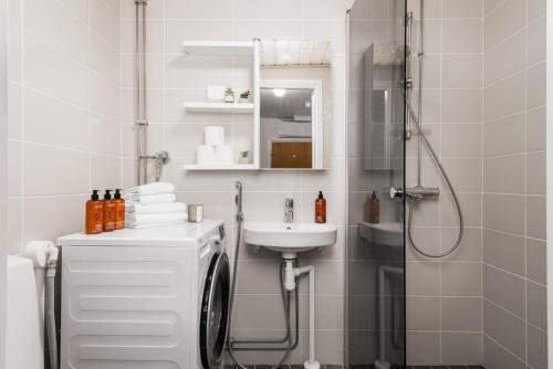 a white bathroom with a sink and a shower at Borg Itsenäisyydenkatu, Centre Spacious 2-Room Apt, King Bed, Free Parking & Wifi in Pori