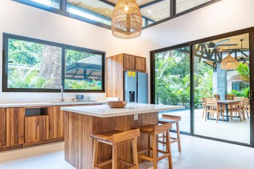 una cucina a pianta aperta con ampia isola, armadi in legno e finestre di Coco Nosara Villas Guiones Family Resort Casa Rubi a Nicoya