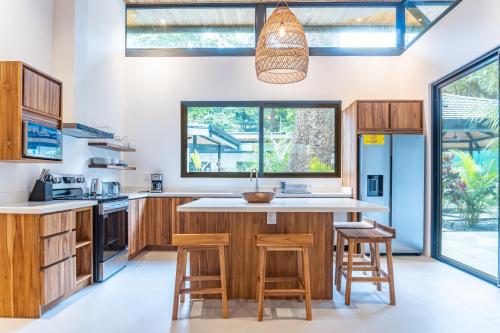 una cucina con armadi in legno e una grande isola con sgabelli di Coco Nosara Villas Guiones Family Resort Casa Rubi a Nicoya