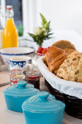 a table with a basket of bread and a bowl of orange juice at Bed and Breakfast De Reggestee in Hellendoorn