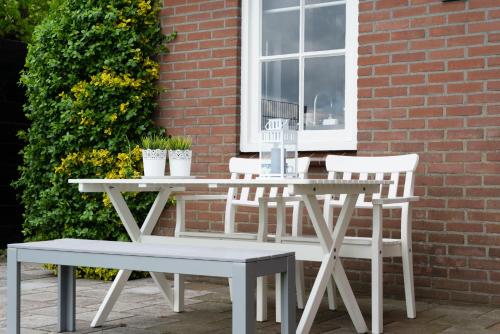 a white table and chairs next to a building at Bed and Breakfast De Reggestee in Hellendoorn
