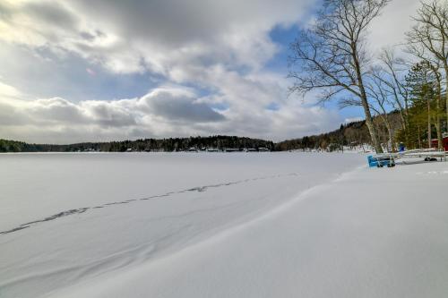 a snow covered lake with a blue bench on it at BBQ Ready Lakeside Milford Home with Paddleboat in Milford