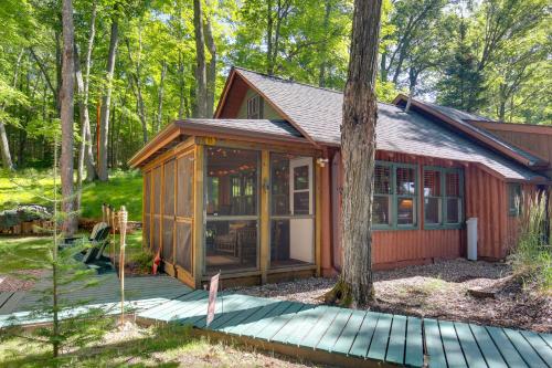 a small cabin in the woods with a wooden deck at Quaint and Cozy Lake Cabin with Dock and Beach Access! in Sayner