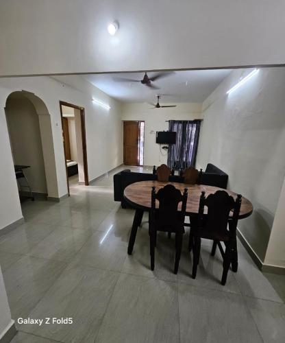 a living room with a wooden table and chairs at Sai Nest in Coimbatore