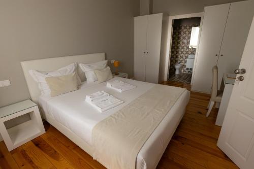 a bedroom with a large white bed with a table at ALM SANTA LUZIA in Guimarães