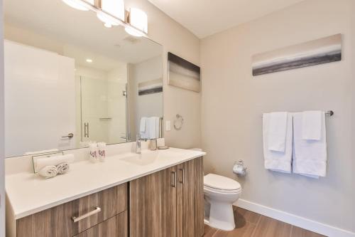 Un baño con lavabo, inodoro y espejo. en Private Apt Seaport with Gym, en Boston