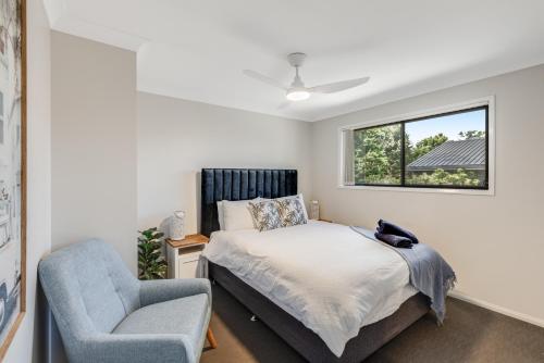 a bedroom with a bed and a chair and a window at Contemporary & Convenient - City Fringe Townhouse! in Toowoomba