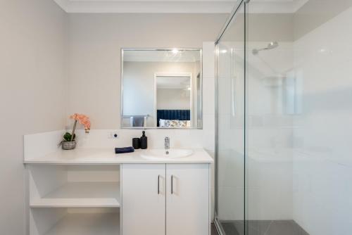 a white bathroom with a sink and a shower at Contemporary & Convenient - City Fringe Townhouse! in Toowoomba