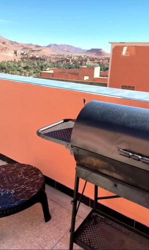 a grill on a balcony with a table and a stool at Home Amazigh Serenity in Tinerhir
