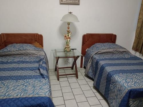 una habitación con dos camas y una mesa con lámpara en Departamento el REPOSO, en Guadalajara