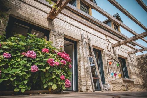 a brick building with a large bush of pink flowers at Chambre dHôtes GALET EN LIN dans Ecolodge ENTRE MER & CAMPAGNE in Octeville-sur-Mer