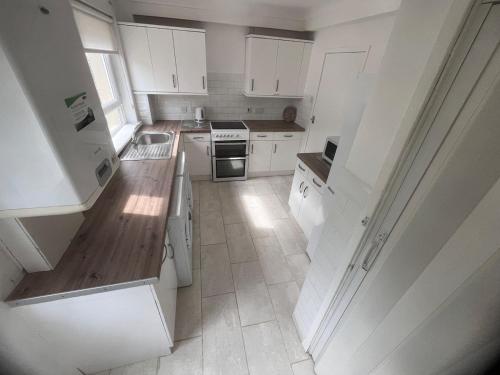 Una cocina con gabinetes blancos y un horno de estufa. en Mitchell House, en Bellshill