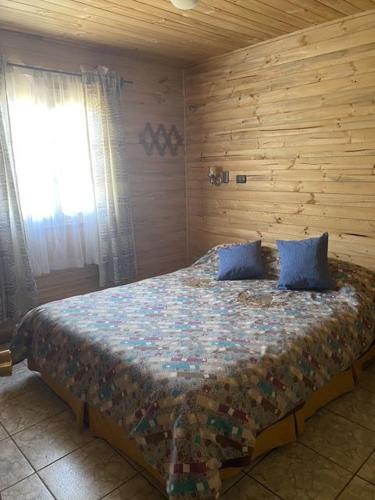 a bedroom with a bed with blue pillows and a window at Casa equipada para 8 personas in Boca Pupuya