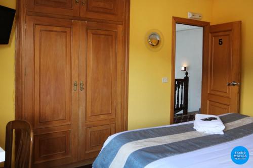 a bedroom with a bed and a wooden closet at Txoko Maitea Pentsioa in Urnieta