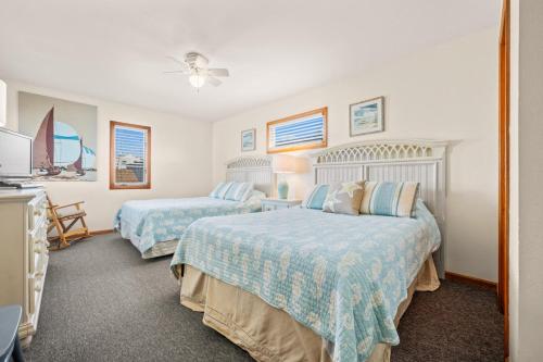 Un dormitorio con dos camas con sábanas azules y blancas. en Summer Nights 4 Bedroom Oceanside Home, en Kill Devil Hills
