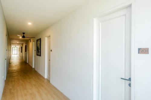 an empty hallway with white walls and wood floors at Urbanview Hotel JJ Bukitsari Semarang in Jatingaleh