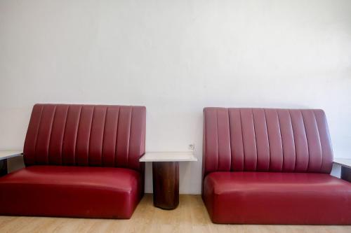 two red chairs and a table in a room at Urbanview Hotel JJ Bukitsari Semarang in Jatingaleh
