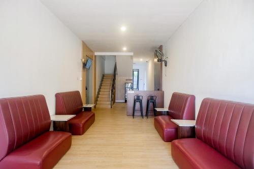 a waiting room with red chairs and tables at Urbanview Hotel JJ Bukitsari Semarang in Jatingaleh