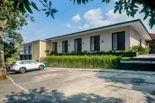 a white house with a car parked in front of it at Urbanview Hotel JJ Bukitsari Semarang in Jatingaleh
