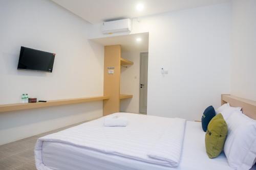 a bedroom with a bed and a tv on the wall at Urbanview Hotel JJ Bukitsari Semarang in Jatingaleh