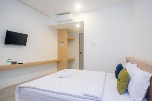a bedroom with a bed and a tv on the wall at Urbanview Hotel JJ Bukitsari Semarang in Jatingaleh