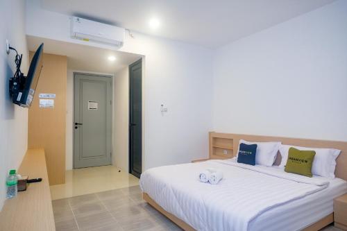 a bedroom with a large white bed in a room at Urbanview Hotel JJ Bukitsari Semarang in Jatingaleh
