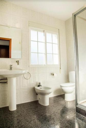 a bathroom with a sink and a toilet and a window at Casa San Vicente in O Grove