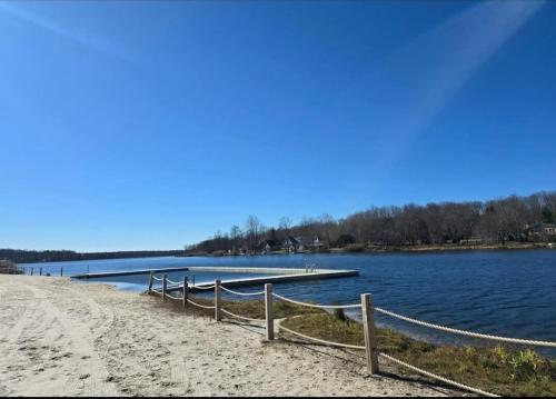 a dock on a beach next to a body of water at Deer Chalet in the heart of Pocono in Tobyhanna