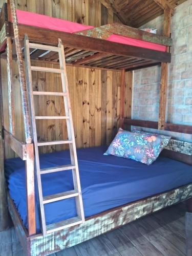 a bunk bed with a ladder in a room at Bangalô de frente pro mar in Imbituba