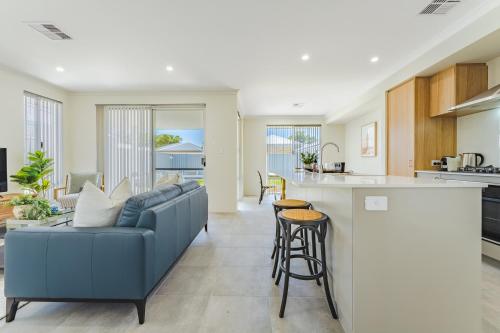 a living room and kitchen with a blue couch in a room at Bright & Airy 3-Bed House Near Rockingham Beach in Rockingham
