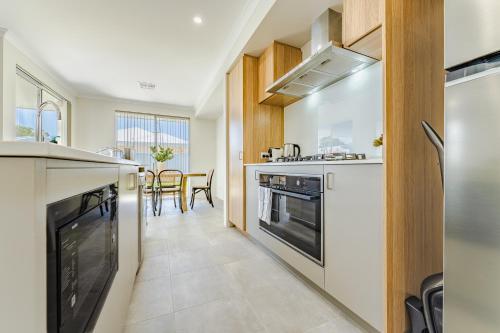 a kitchen with white appliances and a dining room at Bright & Airy 3-Bed House Near Rockingham Beach in Rockingham
