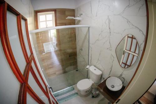 a bathroom with a toilet and a shower with a mirror at Atlantic Pousada in São Sebastião