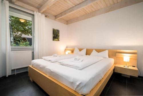a large white bed in a room with a window at Ferienhaus-Unter-den-Eichen-E6 in Röbel